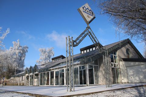 Ein modernes Gebäude im Winter, umgeben von Schnee. Die Architektur ist auffällig mit einem großen, erkennbaren Schild.