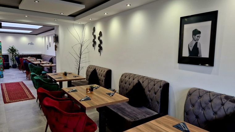 Een modern restaurant met elegante tafels en comfortabele zitgelegenheden. De muren zijn smaakvol gedecoreerd en creëren een uitnodigende sfeer.