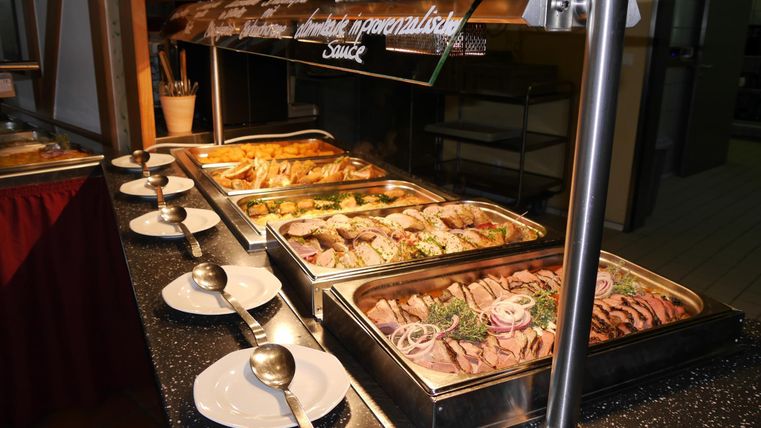 Ein Buffet mit verschiedenen Fleischgerichten und Beilagen. Die Speisen sind schön angerichtet und bereit zum Servieren.