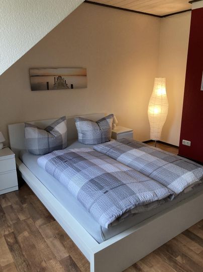 Een gezellige slaapkamer met een tweepersoonsbed en moderne kussens. De warme verlichting zorgt voor een uitnodigende sfeer.