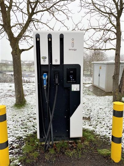 A modern charging station for electric cars stands in a snow-covered landscape. Surrounded by trees and ramps, it offers an elegant solution for eco-friendly driving.