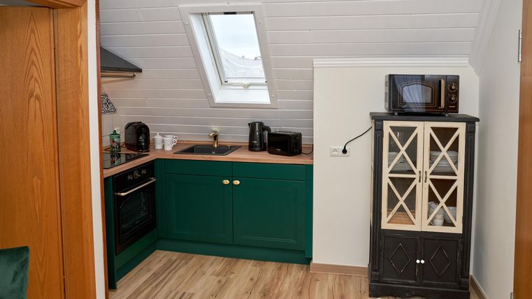 A cozy kitchen nook with green cabinets and modern appliances. The room has a bright skylight that lets in daylight.