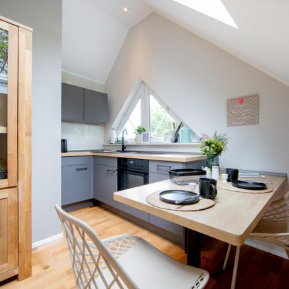 Een moderne keuken met een eetruimte. De ruimte is helder en vriendelijk met een groot raam.