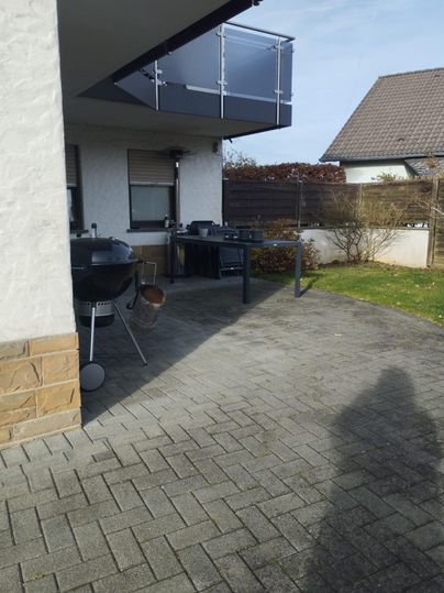 A terrace with a grill and a seating area. In the background,