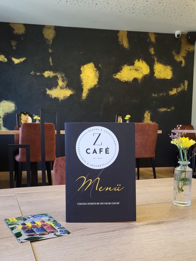Een stijlvol café met een elegant menu op een tafel. Op de achtergrond zijn gezellige stoelen en een kunstzinnige wanddecoratie te zien.