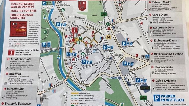 A city map of Wittlich with various sights and dining establishments. Red stickers mark the directions to free toilets.