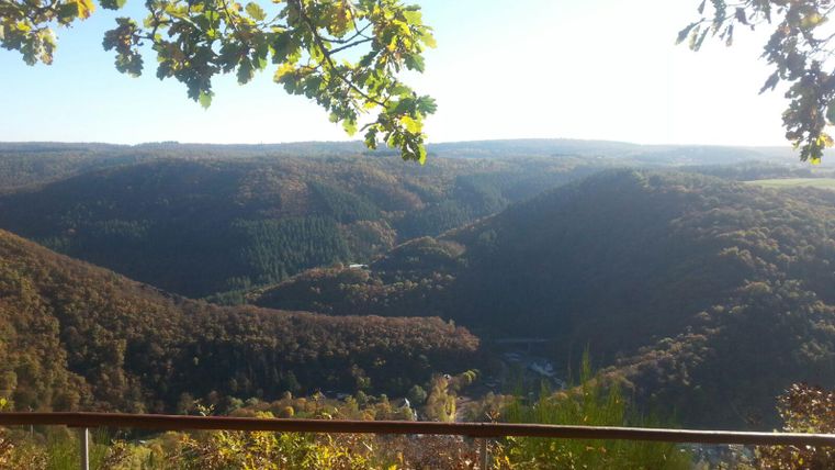 A picturesque view of green valleys and wooded mountains. The sky is clear and the sun is shining.