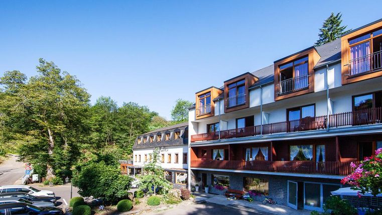 Ein modernes Hotelgebäude umgeben von grüner Natur. Die Balkone bieten einen schönen Blick auf die Umgebung.