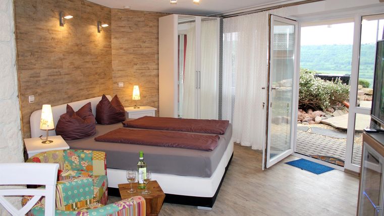 Ein modernes Zimmer mit einem Doppelbett, bunten Möbeln und großen Fenstern. Es bietet einen Blick auf die Natur und hat eine gemütliche Atmosphäre.