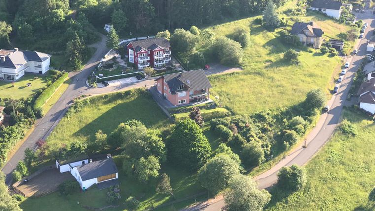 A rural setting with several houses and green meadows. The landscape is surrounded by trees and paths.