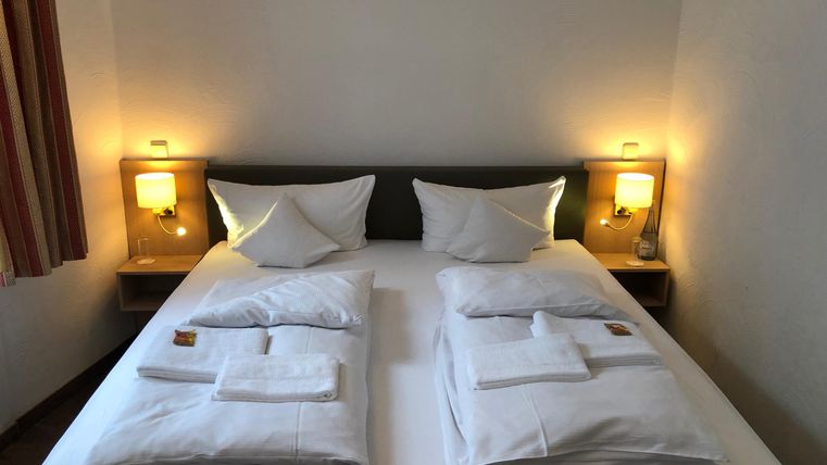 Ein gemütliches Schlafzimmer mit einem Doppelbett und zwei Nachttischen. Die Beleuchtung ist warm und einladend.