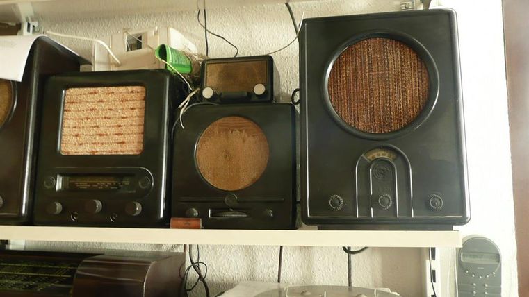 Eine Sammlung alter Radios mit Holz- und Bakelitgehäusen auf einem Regal im Telefonmuseum Gerolstein.