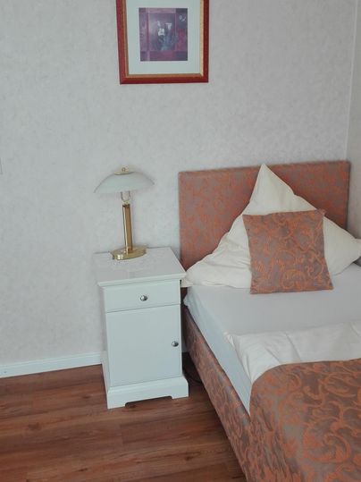 Ein gemütliches Schlafzimmer mit einem Einzelbett und einem Nachttisch. An der Wand hängt ein gerahmtes Bild.