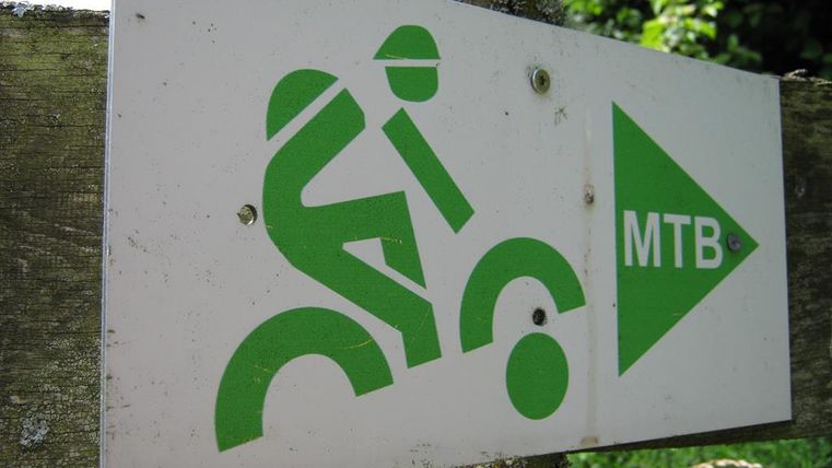 Ein Schild, das einen Mountainbiker zeigt, mit dem Hinweis „MTB“. Das Zeichen ist in grüner Farbe auf einem weißen Hintergrund.