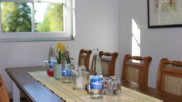 A beautifully set table with water bottles and glasses. The room is brightly lit with a view outside.