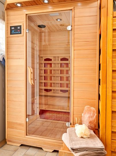 A modern wooden sauna with a glass front. Towels and a salt stone are ready.