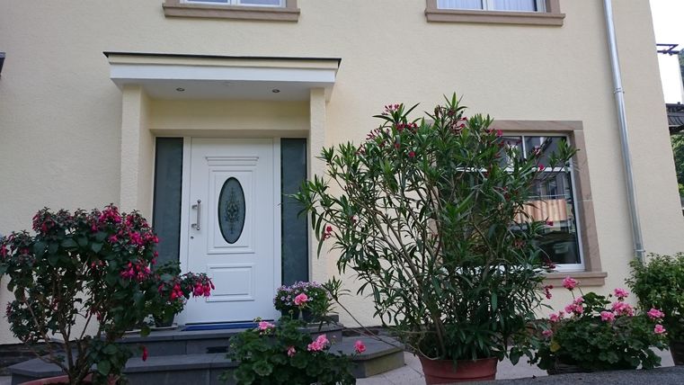Ein schönes Haus mit einer weißen Tür und bunten Blumenumrandungen. Die Pflanzen verleihen dem Eingangsbereich eine einladende Atmosphäre.