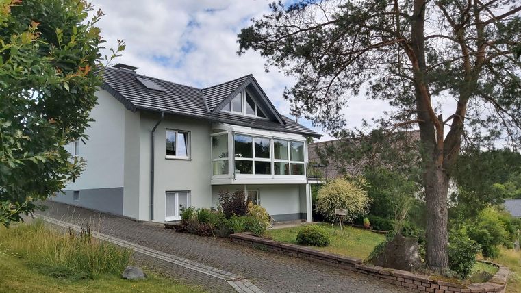 Een modern huis met grote ramen en een goed onderhouden tuin. De omgeving is groen en uitnodigend, ideaal voor een rustige woonatmosfeer.