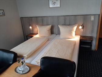 Ein gemütliches Schlafzimmer mit zwei Einzelbetten und sanften Lichtquellen. Ein Tisch mit Stühlen ergänzt den Raum.