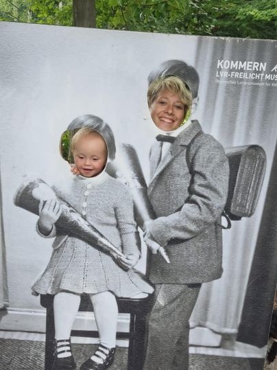 Two children are caught in a photo scene with old schoolchildren. They are posing happily and holding trumpets.