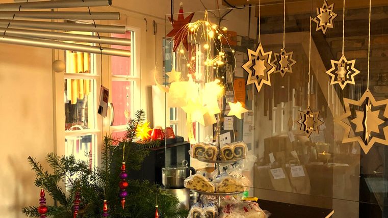 Een feestelijke kerstdecoratie met hangende sterren en lichten. Op de tafel staan koekjes en een kleine kerstboom.