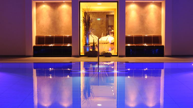 Ein eleganter Wellnessbereich mit einem beheizten Pool und sanftem Licht. Die Umgebung ist einladend und entspannend, ideal für Erholung.