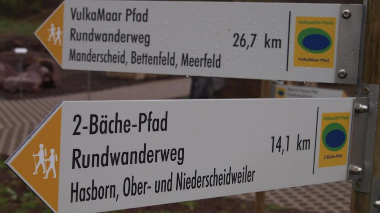 Wegweiser für Wanderwege mit Distanzangaben. Der Volksmoor-Pfad ist 26,7 km lang und der 2-Bäche-Pfad hat eine Länge von 14,1 km.