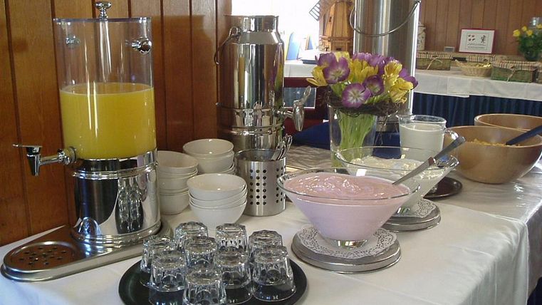 A buffet with various drinks and foods. There is juice, yogurt, and a selection of bowls and glasses.