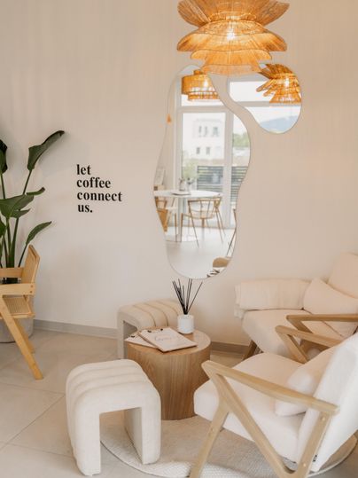 Ein stilvolles Café mit bequemen Möbeln und warmen Lichtakzenten. An der Wand steht der Spruch: "let coffee connect us."