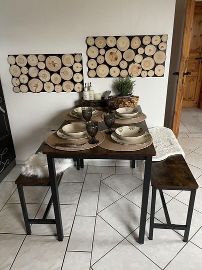 Een gezellige eetruimte met een tafel en twee banken. De tafel is stijlvol gedekt met servies, glazen en decoratieve elementen.