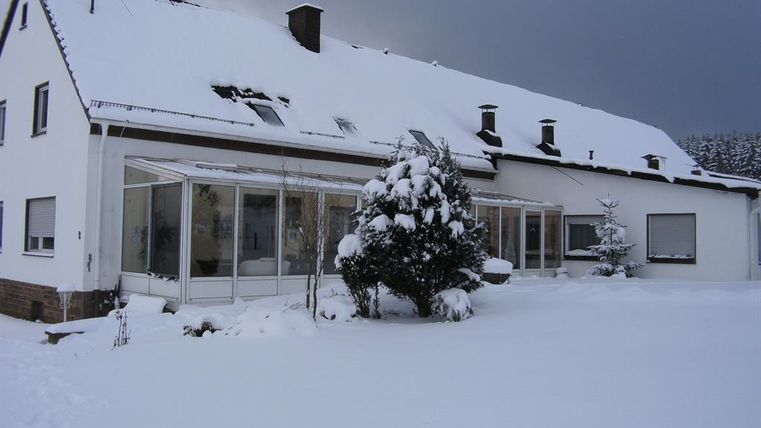 Ein Haus im Schnee mit einem Wintergarten. Die Umgebung ist von einer dicken Schneeschicht bedeckt.