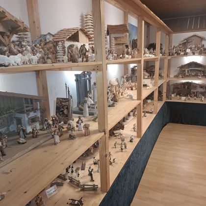 Eine detaillierte Ausstellung mit zahlreichen Holzfiguren und Miniaturlandschaften. Die Figuren sind organisiert in Regalen und zeigen verschiedene Szenen.