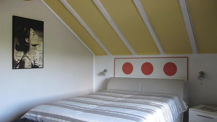 Ein gemütliches Schlafzimmer mit einem großen Bett und einer modernen Einrichtung. An der Wand hängen ein Kunstwerk und runde Dekorationen.