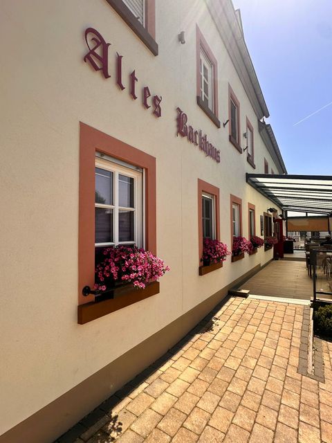 A charming building with the inscription "Old Bach House." Flower boxes with colorful flowers adorn the windows.