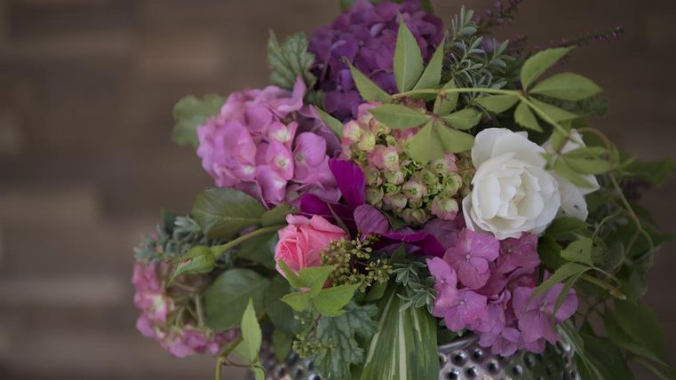 Een mooie bos bloemen met roze, paarse en witte bloeien. De bloemen zijn in een zilveren vaas gerangschikt en vullen elkaar harmonieus aan.