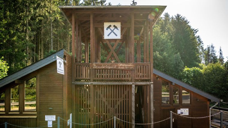 A wooden building with a observation tower that recalls a former mining site. Surrounded by trees, it exudes a rustic charm.