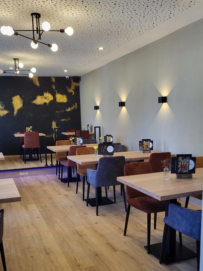 Een modern restaurant met houten vloeren en elegante tafels. De muren zijn in zachte kleuren ingericht, aangevuld met warm licht en decoratieve elementen.