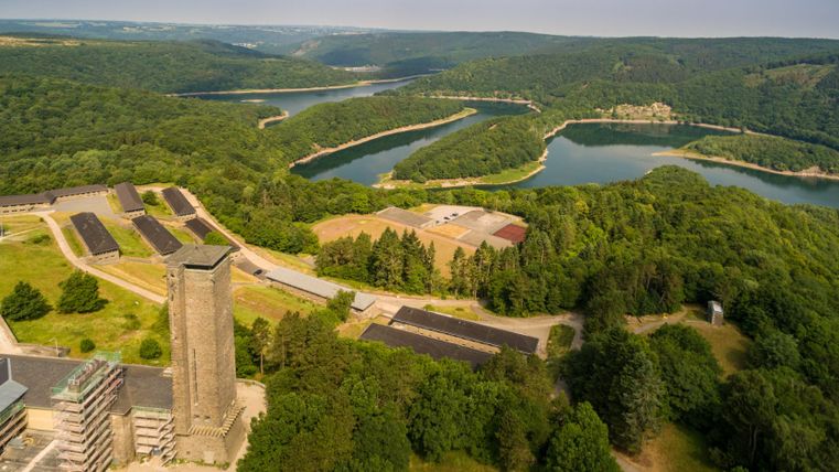 Luftaufnahme von Vogelsang und Urftsee in einer grünen Waldlandschaft.