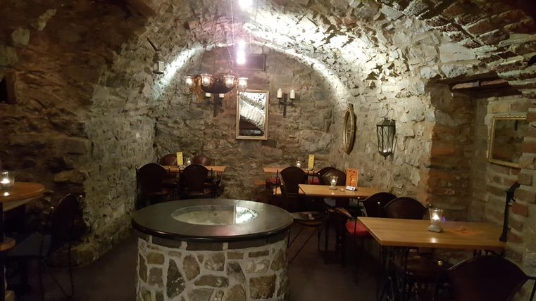 A cozy cellar with stone walls and rustic wooden tables. Soft light creates an inviting atmosphere.