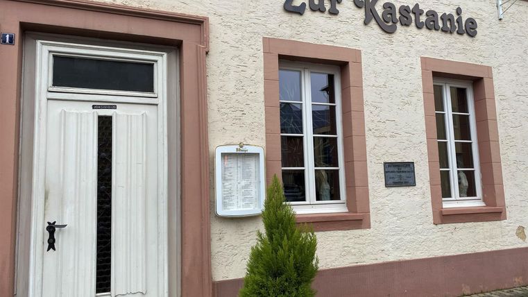 Ein traditionelles Restaurant mit dem Namen "Zur Kastanie". Die Fassade zeigt einladende Fenster und eine ordentlich gestaltete Eingangstür.