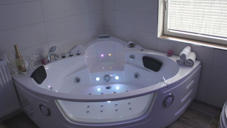 Ein moderner Whirlpool in einem hellen Badezimmer. Er ist mit bunten Lichtern und verschiedenen Funktionen ausgestattet.