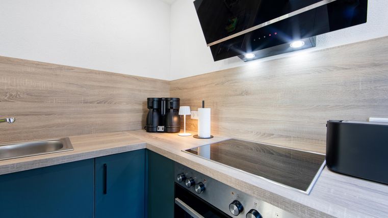 Eine moderne Küche mit einem eleganten Design. Die Holzoptik und die schwarzen Geräte verleihen der Küche einen stilvollen Look.