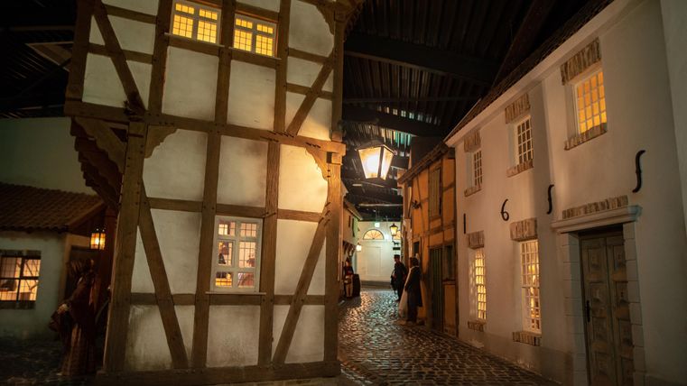 A picturesque street with historic buildings and warmly lit windows. The cobblestone street creates a cozy atmosphere.