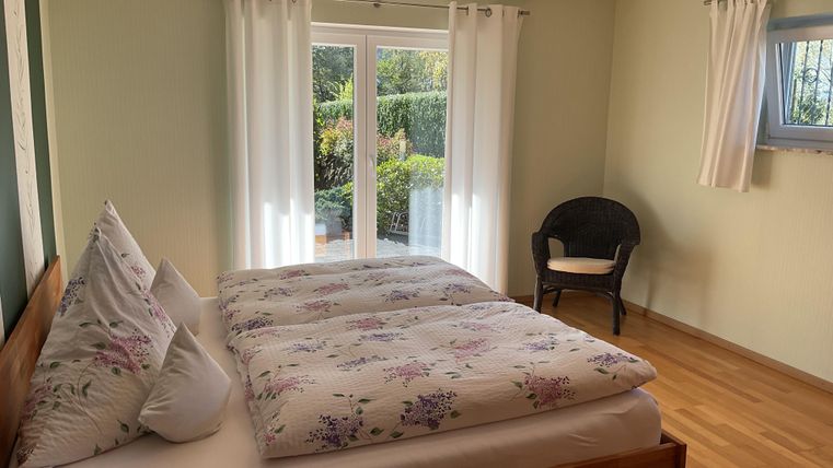 A cozy bedroom with a double bed and a view of the garden. The large windows let in plenty of light and create a pleasant atmosphere.