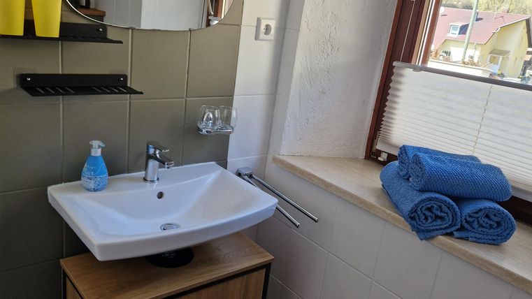 Een moderne badkamer met een wastafel en een grote spiegel. Handdoeken en toiletartikelen zijn netjes gerangschikt.