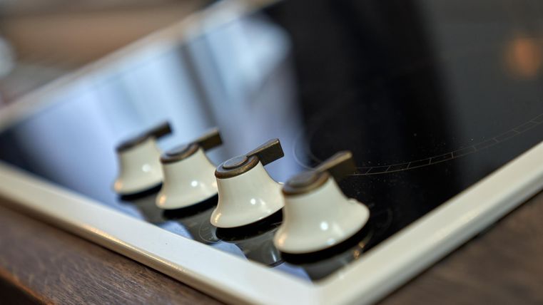 A modern cooking hob with four controls. The elegant surface is black and reflects the light.