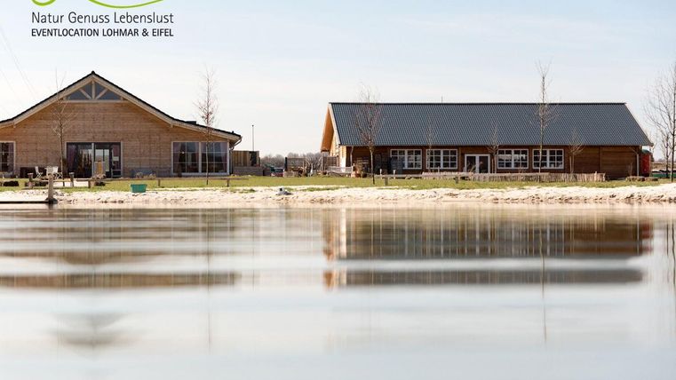 A tranquil lake with reflective water, surrounded by modern buildings. The architecture is friendly and inviting, ideal for events.
