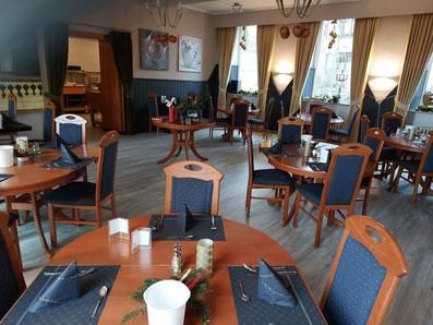 Ein einladendes Restaurant mit Holztischen und blauen Stühlen. Das Licht fällt durch große Fenster und schafft eine warme Atmosphäre.