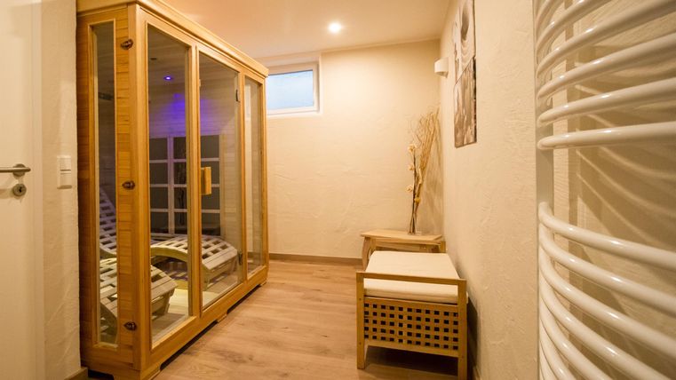 A cozy wellness area with a sauna and a small space to relax. The walls are bright, and the light creates a calming atmosphere.