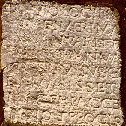 An old stone inscription with engraved letters. The characters are partly weathered and illegible.